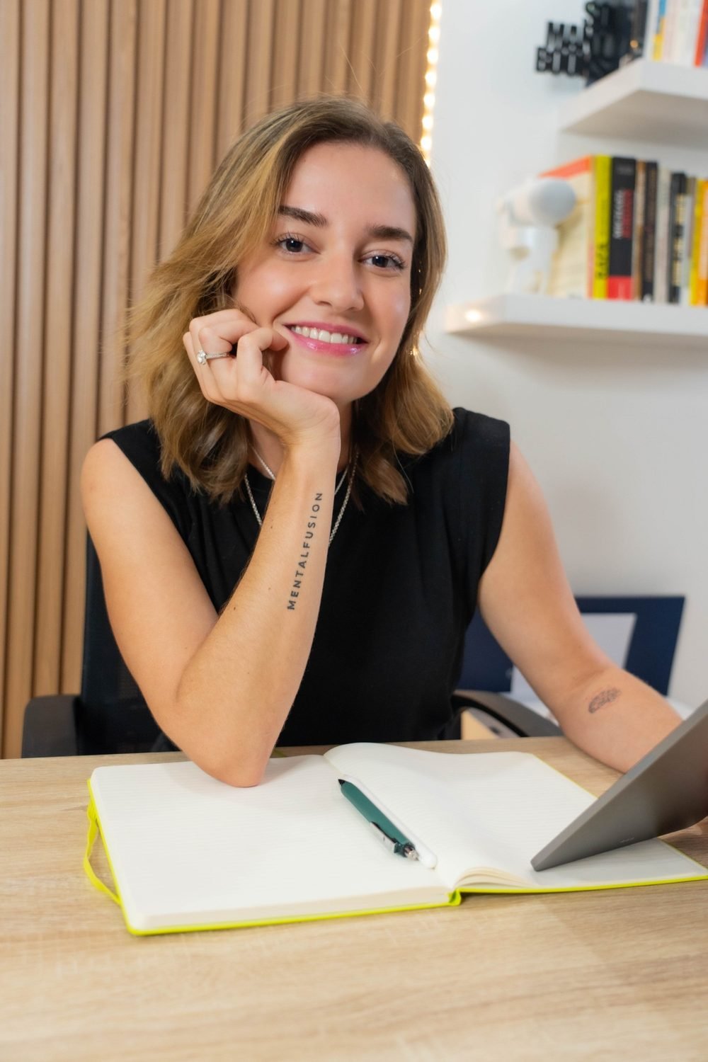 María Fernanda Rodríguez sonriendo en su escritorio, con el tatuaje de MentalFusion en el brazo